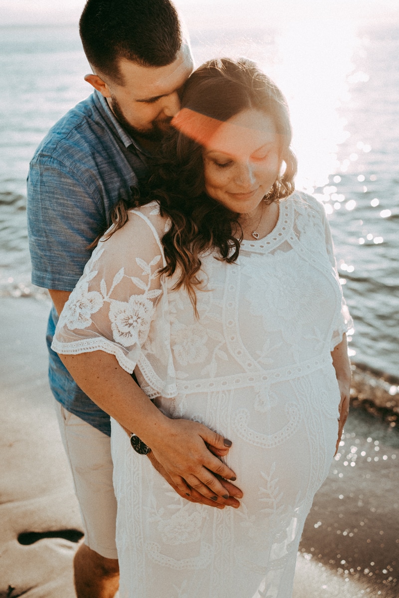 Seattle Maternity Photography, a man holds his expecting wife from behind, she guides his hands to her pregnant belly