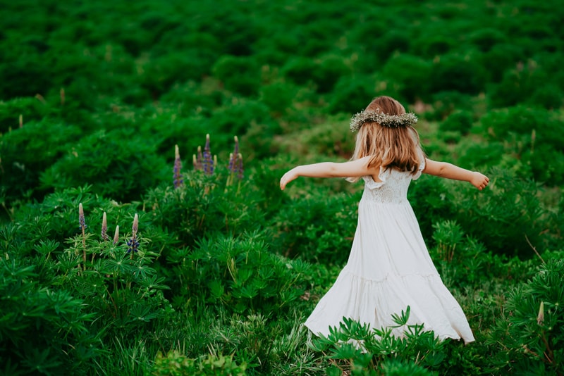 Seattle Motherhood Photography, a girl dances within the shrubbery outdoors, wild lavender grows nearby
