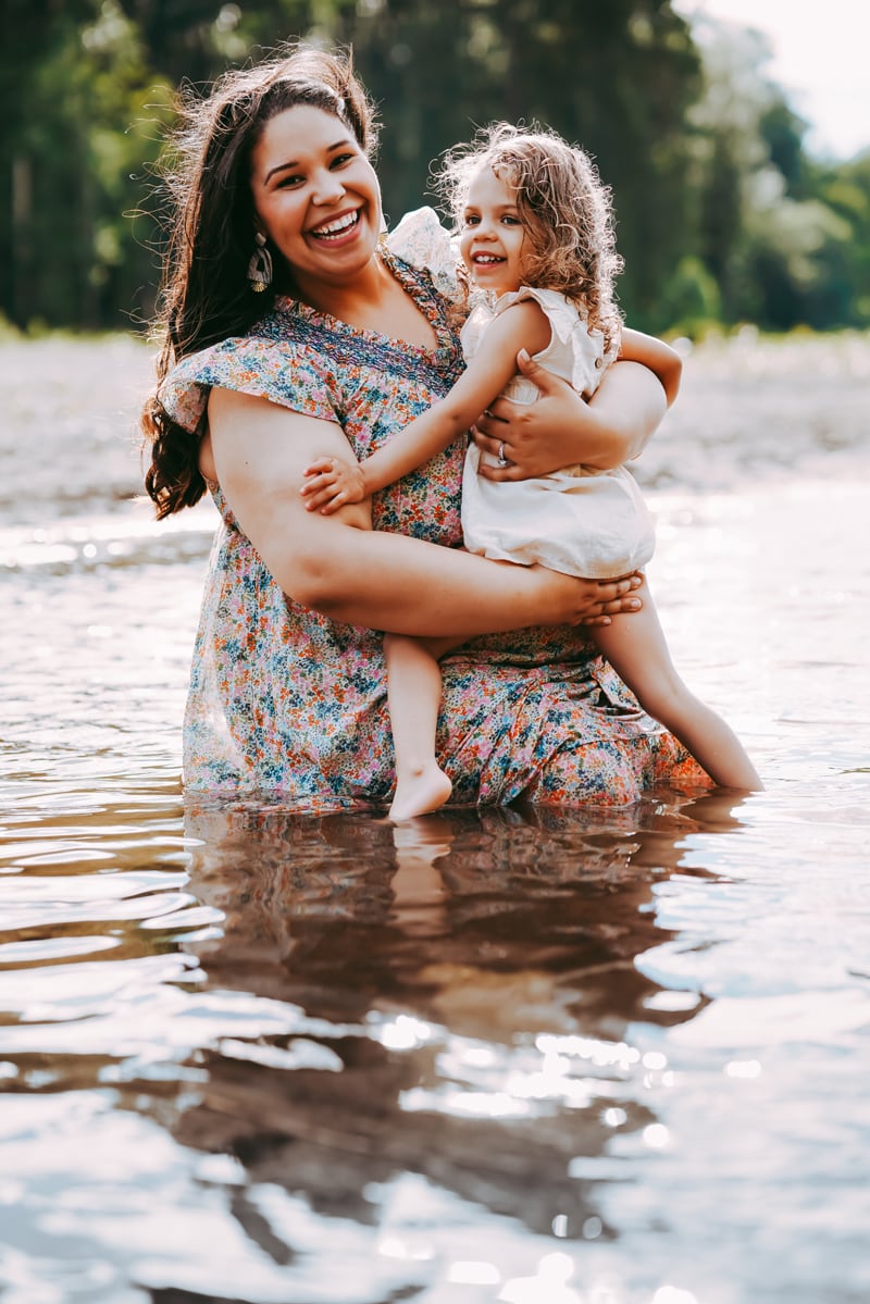 Seattle Maternity Photography, Happy expecting mother holds toddler daughter in a forest river