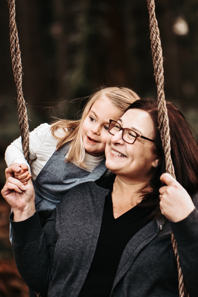 Seattle Grandparent Legacy Photography, A Grandmother sits on a swing with her granddaughter, they both have big smiles