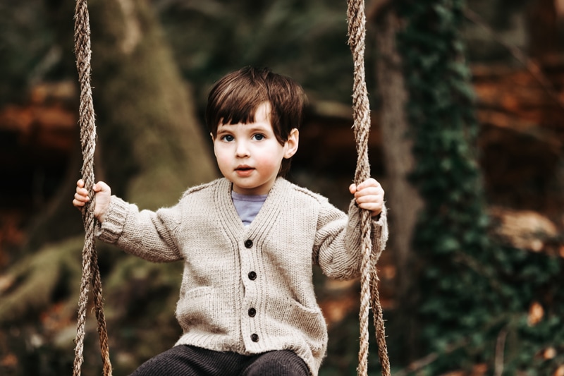 Seattle Motherhood Photography, a boy sits curiously on a tree swing in the forest