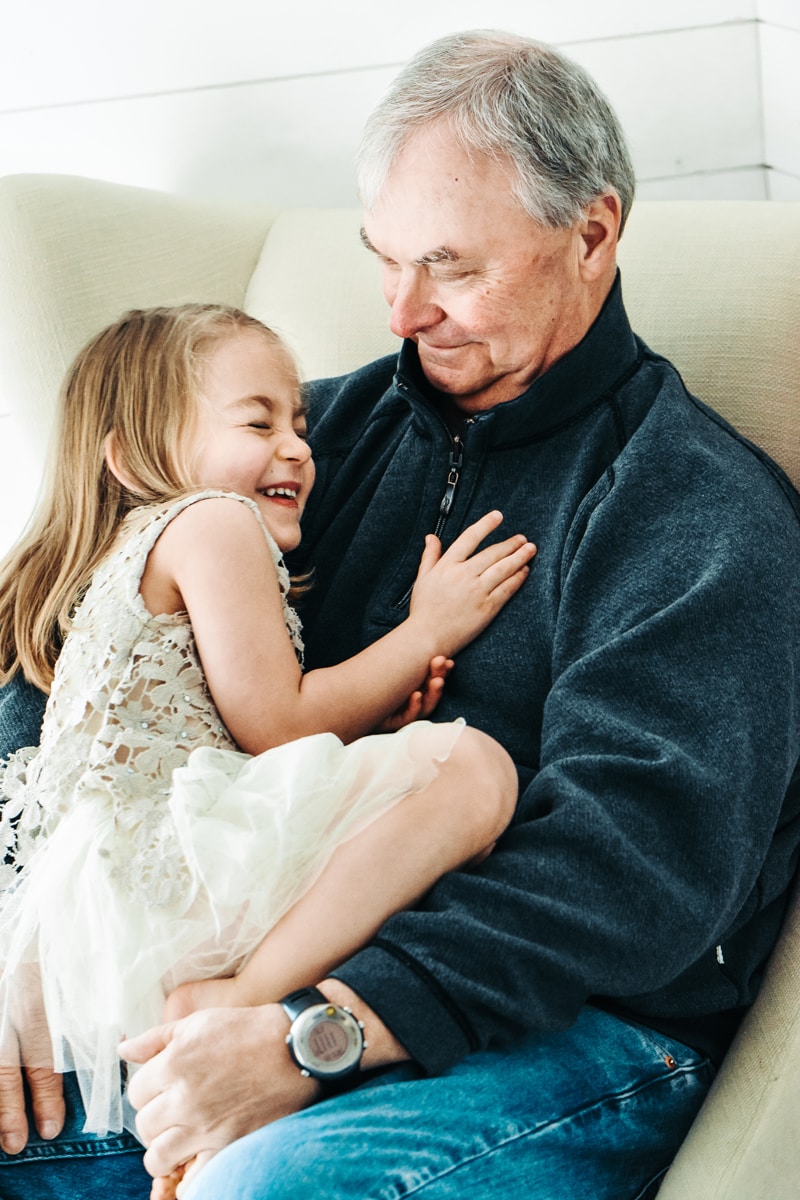 Seattle Grandparent Legacy Photography, a proud and happy grandpa looks into his giggling granddaughter's eyes as she sits on his lap