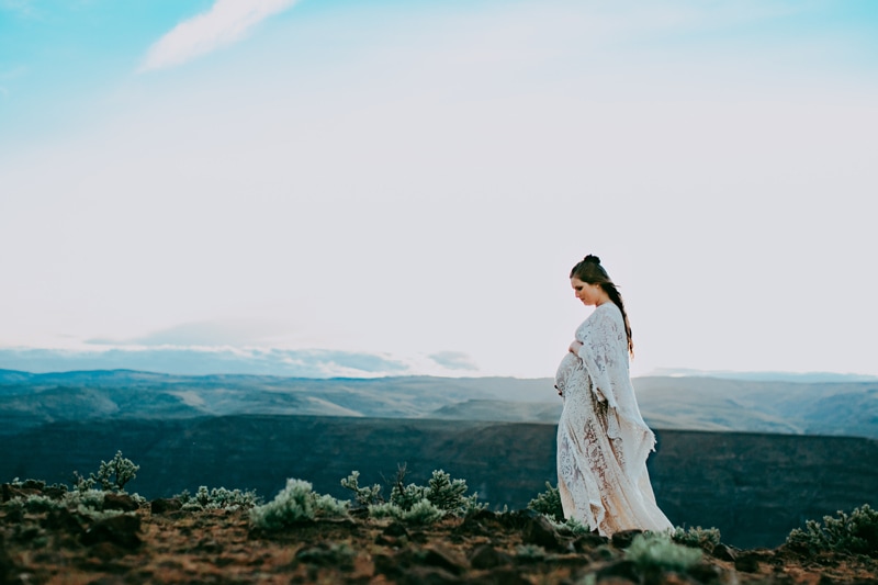 Seattle Maternity Photography, a woman stands on a ridge line with rolling hills behind her, she is expecting