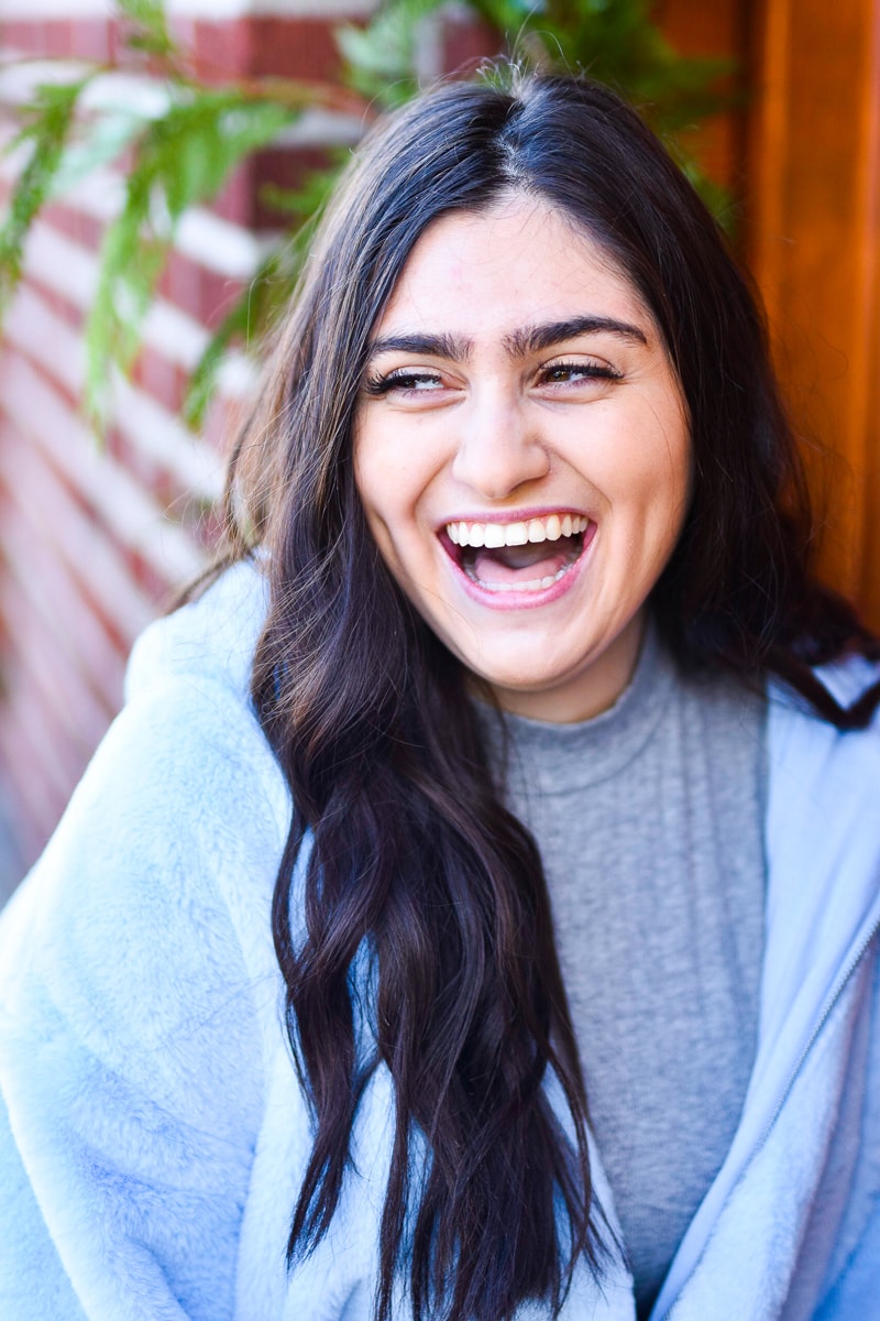 Seattle Senior Photography, a high school woman smiles and laughs outdoors near a brick wall