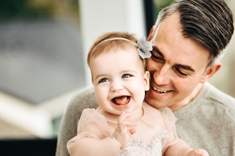 Seattle Motherhood Photography, dad admires his daughter and she smiles, a bow in her hair