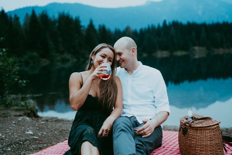 Seattle Couples Photography, man and woman enjoy a glass of wine on a picnic blanket near the lake